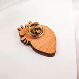 A handcrafted wooden keychain shaped like an anatomical heart with a gold metal key ring attached, resting on a white fabric background—a true statement piece for any collection.