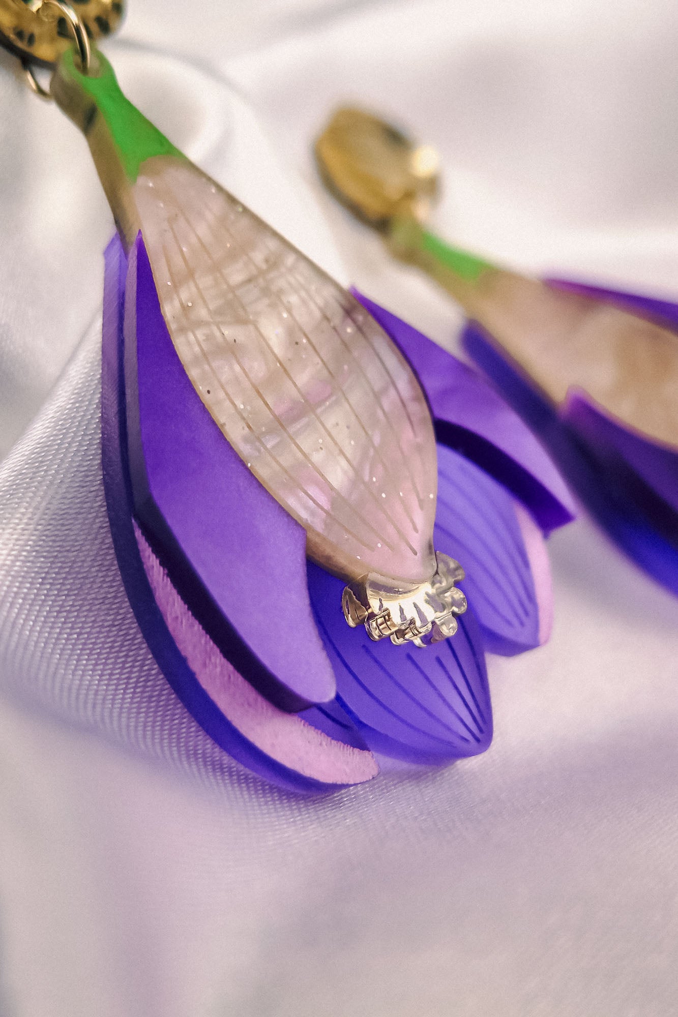 Close-up of handcrafted Crocus Flower Earrings, a statement accessory shaped like purple blossoms with layered petals and a translucent, textured center, resting on a white fabric background.