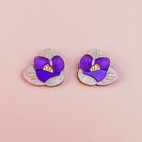 Crocus Stud Earrings featuring hand-painted flowers in purple and white with yellow centers, beautifully displayed on a light pink background.