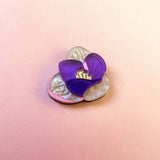 A handcrafted Purple Crocus Flower Lapel Pin, this decorative brooch features pearly cream petals and a translucent purple petal, perfect for nature lovers, set against a soft pink gradient background.