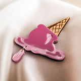 A handcrafted Melted Ice Cream Brooch, shaped like a melting pink scoop on a waffle cone, rests on a smooth, cream-colored fabric background—perfect for adding charm to your summer wardrobe.