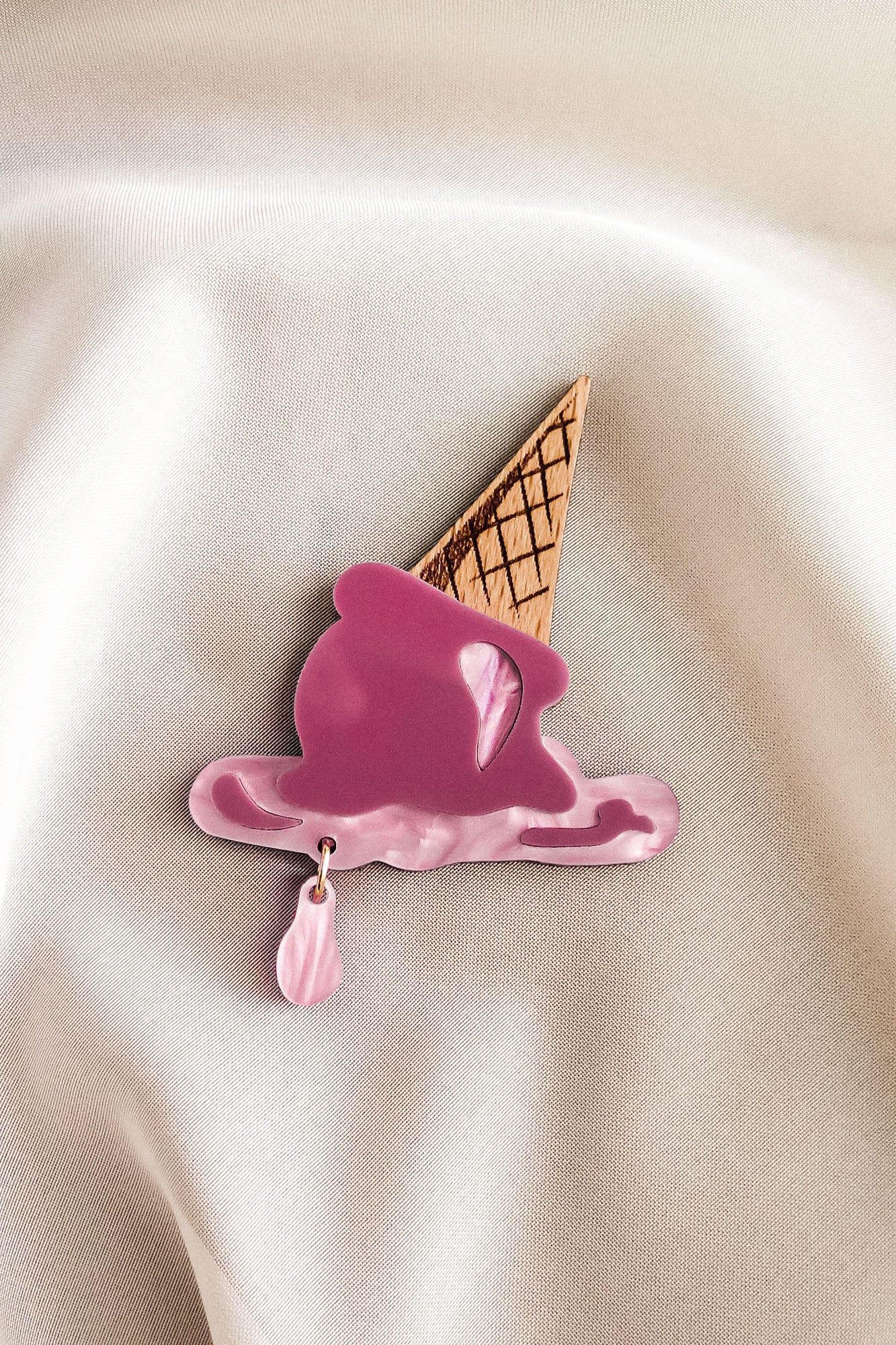 Add a touch of whimsy to your summer wardrobe with this handcrafted Melted Ice Cream Brooch, shaped like a pink melting scoop atop a waffle cone on creamy fabric, finished with a dangling pink drop.