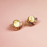 A pair of Minimalist Geometric Stud Earrings featuring round gold tops and semi-circular, iridescent bases, displayed on a pink background.