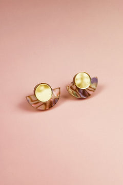 A pair of Minimalist Geometric Stud Earrings featuring round gold tops and semi-circular, iridescent bases, displayed on a pink background.