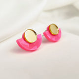 Minimalist Geometric Stud Earrings featuring gold circular tops and bright pink, semi-circular acrylic bases. Lightweight and hypoallergenic, they’re displayed on a soft white surface for a modern, stylish touch.