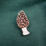 A handcrafted Morel Mushroom Pin is attached to a green, ribbed fabric, likely on a shirt or sweater.