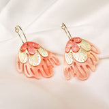 A pair of decorative Organic Floral Hoops featuring pink translucent petal-like acrylic flowers and gold accents, displayed on a soft white fabric background.