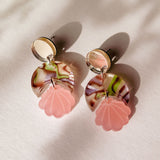 A pair of lightweight, handmade Seashell Earrings featuring round mirrored studs, marbled pink and brown circles, and pink shell-shaped pendants, displayed on a light surface with soft shadows.