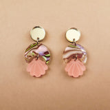 Handmade gold and marbled pink Seashell Earrings with circular tops, lightweight translucent marbled middles, and pink shell-shaped pendants, displayed on a light beige background.